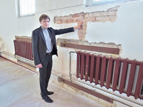 Владимир Татарников показывает, как металлическими пластинами стягиваются  трещины на стенах храма
