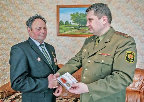 Военный комиссар Вилейского района Юрий Ганчиевский вручает Ивану Станкевичу очередную юбилейную медаль.